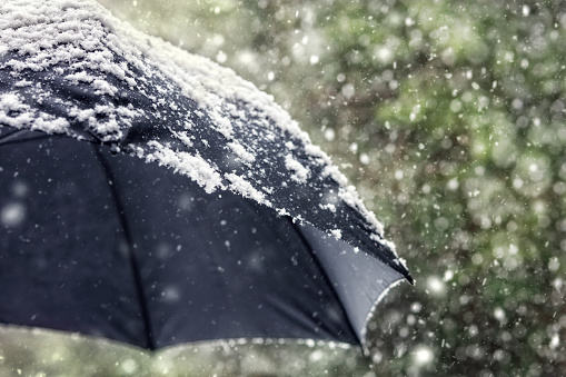 Snow flakes falling on a black umbrella concept for bad weather, winter or snowing blizzard