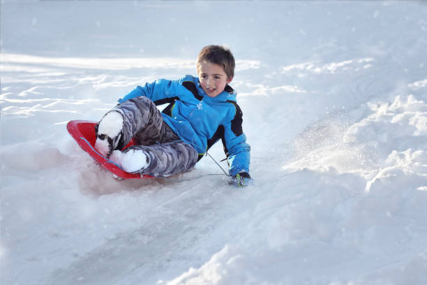 istock Boy sledding down a hill in the snow 1079018914