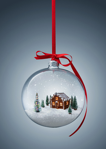 Cozy christmas gingerbread house in glass ball over gray background with copy space