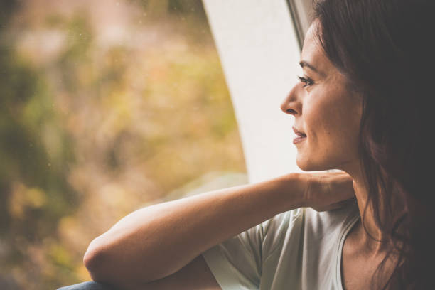 istock Pensive woman looking through window 1079028906
