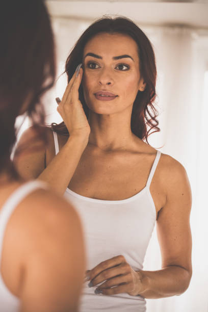 istock Woman applying face foundation in front of mirror 1079029100