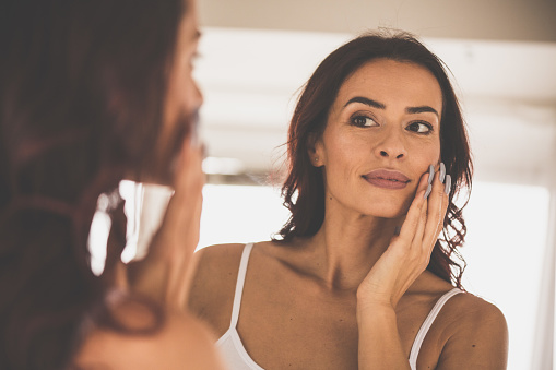 Portrait of a beautiful woman doing her everyday beauty routine in front of mirror.