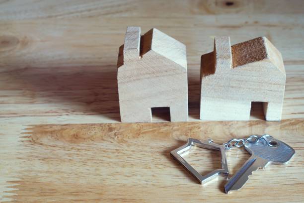Home key with home keyring and wooden house model on bright background, real estate concept, copy space stock photo