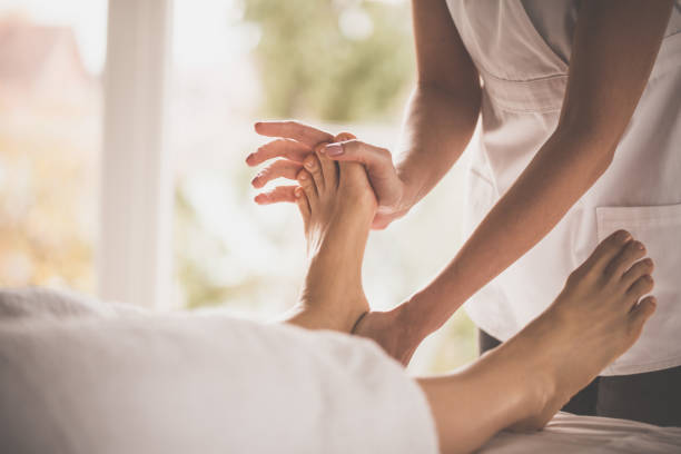 female hand doing foot massage at the spa - reflexology human foot spa treatment health spa imagens e fotografias de stock