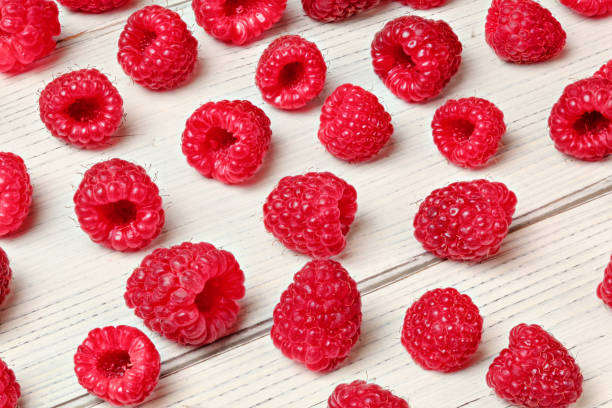 istock Raspberries spilled on white boards desk. 1079059868
