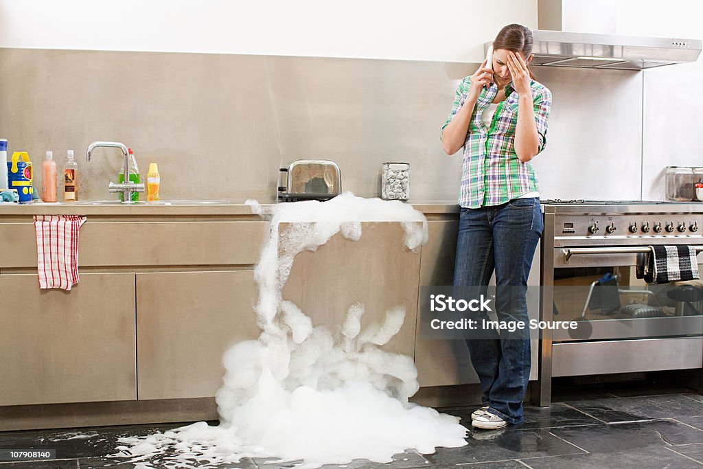 Young woman on phone with overflowing dishwasher  Dishwasher Stock Photo