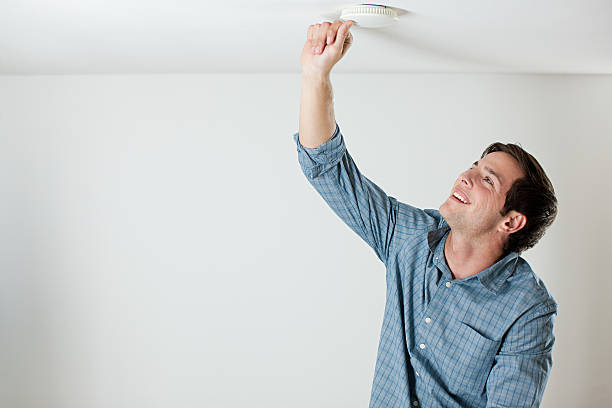 Young man testing smoke alarm on ceiling  smoke detector photos stock pictures, royalty-free photos & images