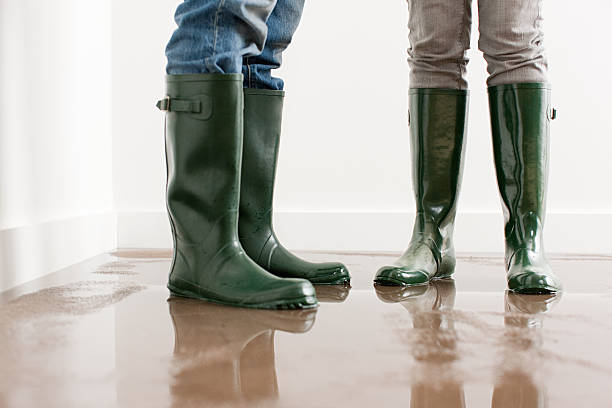 young couple in wellington boots on flooded floor - жилищные трудности стоковые фото и изображения