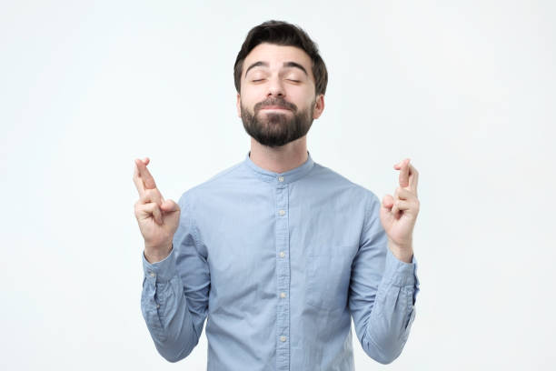 istock Hispanic man standing with crossed fingers and closed eyes, having pleading expression 1079091944