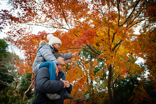 Father and daughter looking at autumn leaves with a shoulder car
