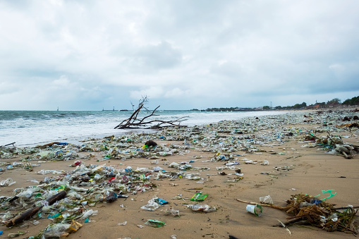 Garbage on beach, environmental pollution in Bali Indonesia. Drops of water are on camera lens. Dramatic view