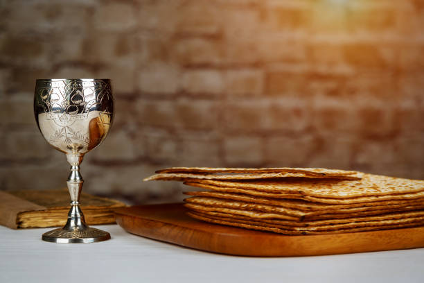 Silver wine cup with matzah, Jewish symbols for the Passover Pesach holiday. Passover concept. Jewish Matzah on Decorated Silver wine cup with matzah, Jewish symbols for the Passover Pesach holiday. Passover concept. passover celebration stock pictures, royalty-free photos & images