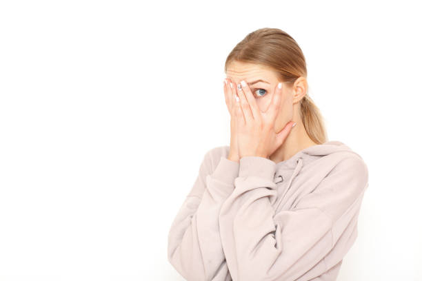 istock Beautiful young female peeks though fingers, covers face with both hands, has frightened expression as notices something terrible or scarying, isolated over white background. 1079109048