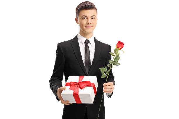 istock Elegantly dressed handsome teenage boy holding a present and a rose 1079109544