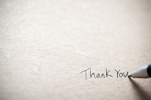 Hand writing thank you on piece of old grunge paper