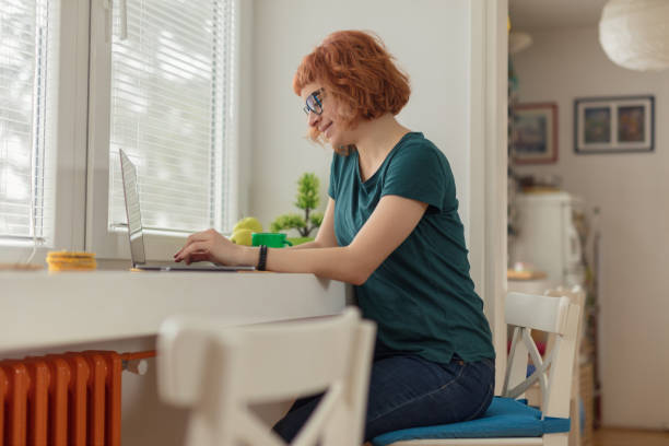 istock Smiling young woman working on her laptop and drinking coffee 1079134594