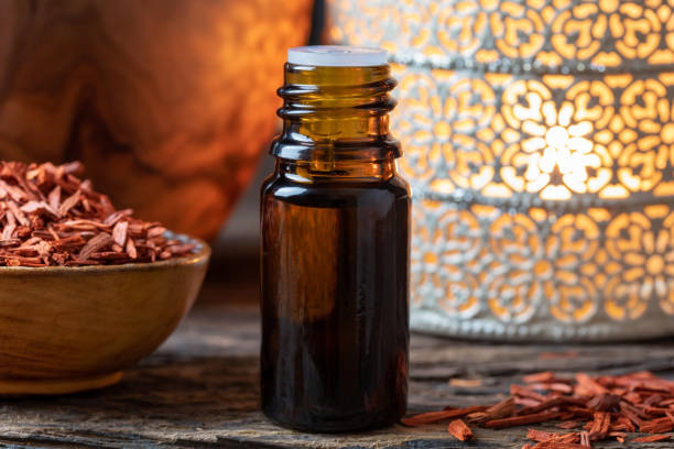 una bottiglia di olio essenziale di sandalo con chips di sandalo rosso - legno di sandalo foto e immagini stock