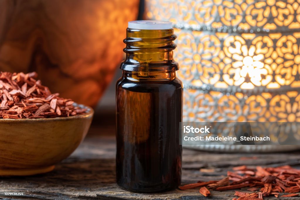 A bottle of sandalwood essential oil with red sandalwood chips Sandalwood Stock Photo