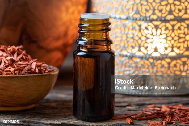 A Bottle Of Sandalwood Essential Oil With Red Sandalwood Chips Stock Photo - Download Image Now