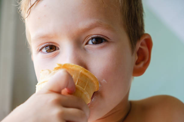 istock Small boy with charming eyes is holding and eating ice-cream 1079149394