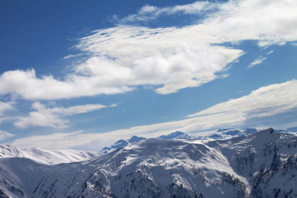 Snowy mountains and sunlight blue sky with clouds at winter evening. Caucasus Mountains. Svaneti region of Georgia.