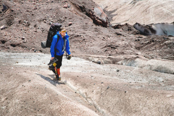 istock A mountaineer with a backpack walks in crampons walking along a dusty glacier with sidewalks in the hands between cracks in the mountain 1079157242