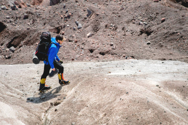 istock A mountaineer with a backpack walks in crampons walking along a dusty glacier with sidewalks in the hands between cracks in the mountain 1079159444