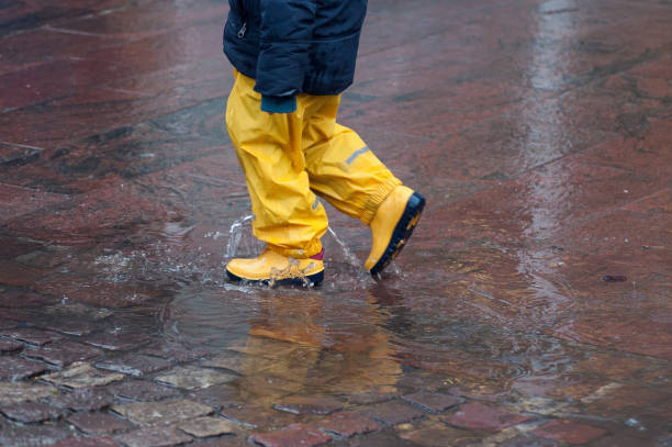 istock boy playing in puddle of water with yellow boots 1079159824