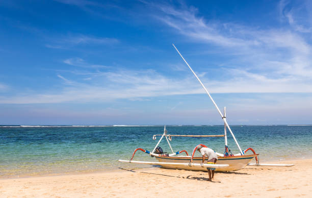 Bali, Indonesia - April 26, 2018: Fisherman preparing his boat on balinese shore in Indonesia