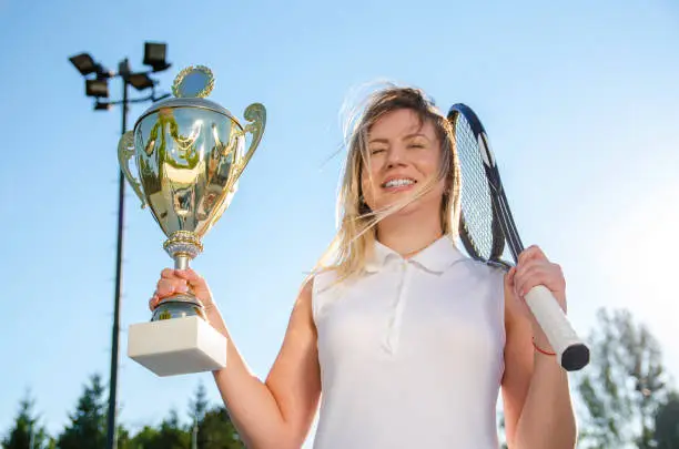 Photo of Happy woman tennis player exited holding big trophy