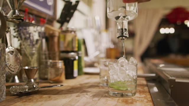 A Woman Bartender Prepares a Mixed Drink Mojito at a Bar (with Muddled Mint, Ice, and Rum)