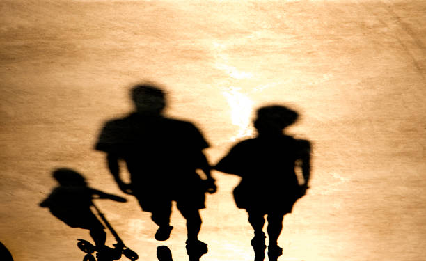 istock Blurry shadow of parents with a child on a push scooter 1079175690