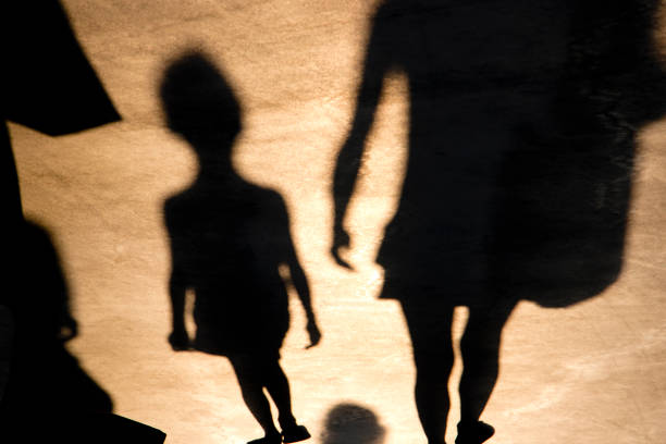 Blurry shadow of a child and mother walking on promenade in summer sunset