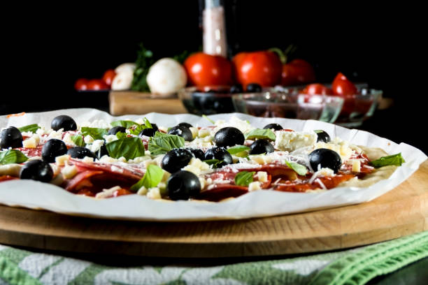 istock Raw uncooked pizza with pepperoni salami, black olives, basil and cheese. 1079185298