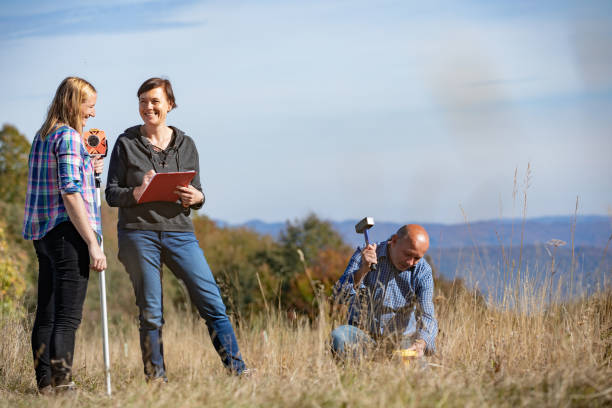 istock Surveyor Hammering Boundary Marker in Meadow 1079202280