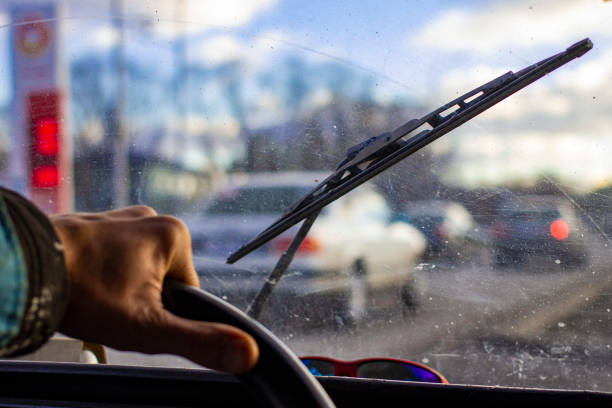 istock dirty scratched car windshield with wiper through blurred steering wheel with driver's hand on blurred background 1079237954