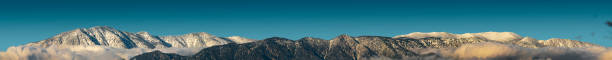 A panorama of the southern face of the San Bernardino Mountains in southern California after a winter storm, with Mount San Bernardino (10,649 ft, 3246 m) on the far left, Anderson Peak left of center (10,840 ft, 3304 m), and the highest mountain in southern California, Mount San Gorgonio, at the far right of the ridge on the right (11,502 ft, 3506 m).  Mount San Gorgonio is also called \