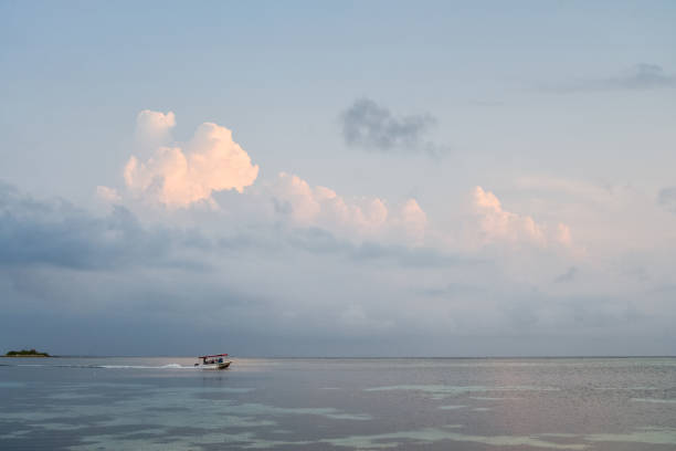 Blue sky with clouds on sunrise, sea and boat with people on Maldives