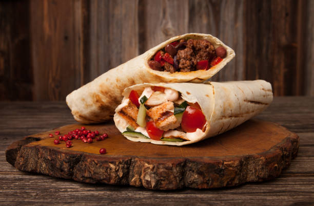 Burrito and shawarma wraps with beef and pork vegetables on wooden table. Copy space for text. stock photo