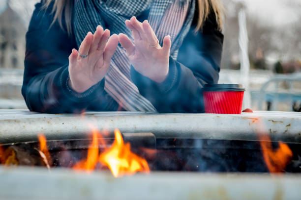 Woman warming herself up near a campfire in a Christmas market on a cold day of winter at Atwater Market, Montreal, Canada