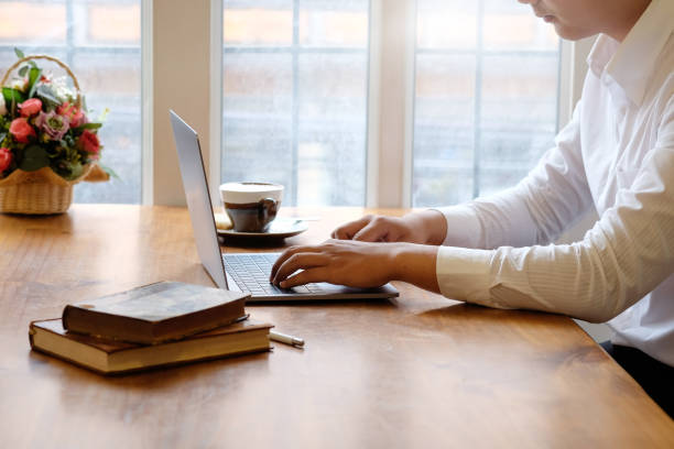 istock Cropped Man using laptop computer and books with coffee on office desk. 1079401974