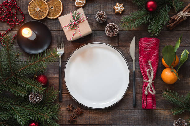 Authentic Christmas Table Setting Authentic Christmas Table Setting. Empty Plate, Candles, Silverware, Fir tree, Gift boxes. Top view with copy space for text restaurant table layout stock pictures, royalty-free photos & images