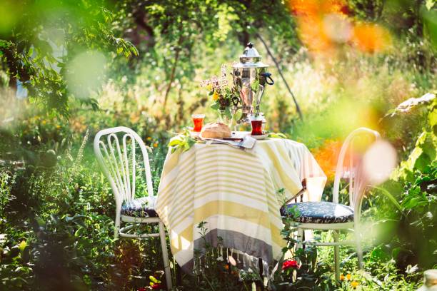 Tea set ceremony in garden setting, summer outdoors breakfast with fresh bread and rose jam and samovar