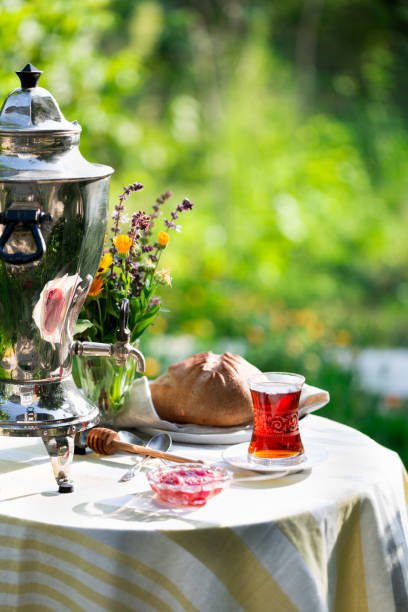 istock Tea set ceremony in garden setting, summer outdoors breakfast with fresh bread and rose jam and samovar 1079483146
