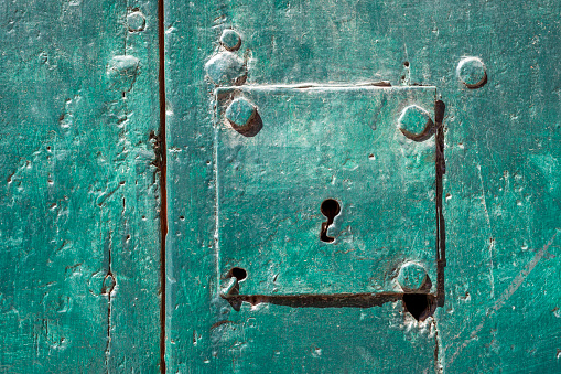 detailed background of green metallic door with focus on keyhole