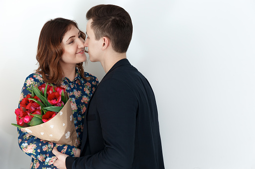 Romantic couple kissing, woman with tulip bouquet. 8 march gift, love relationship