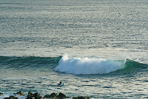 Man swimming on surfboard for catching waves on Pacific ocean, Hanga Roa, Easter Island, Chile