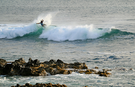 Surfer riding on the breaking waves in Pacific Ocean at Hanga Roa, Easter Island, Chile