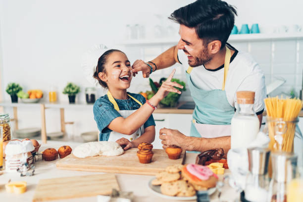 Father and daughter having fun in the kitchen Father and daughter preparing cupcakes together flour mess stock pictures, royalty-free photos & images