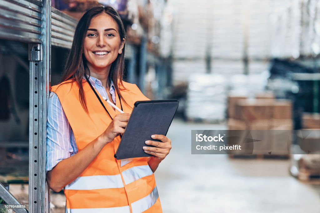 Warehouse manager with digital tablet Smiling young woman with digital tablet in a large warehouse Warehouse Stock Photo